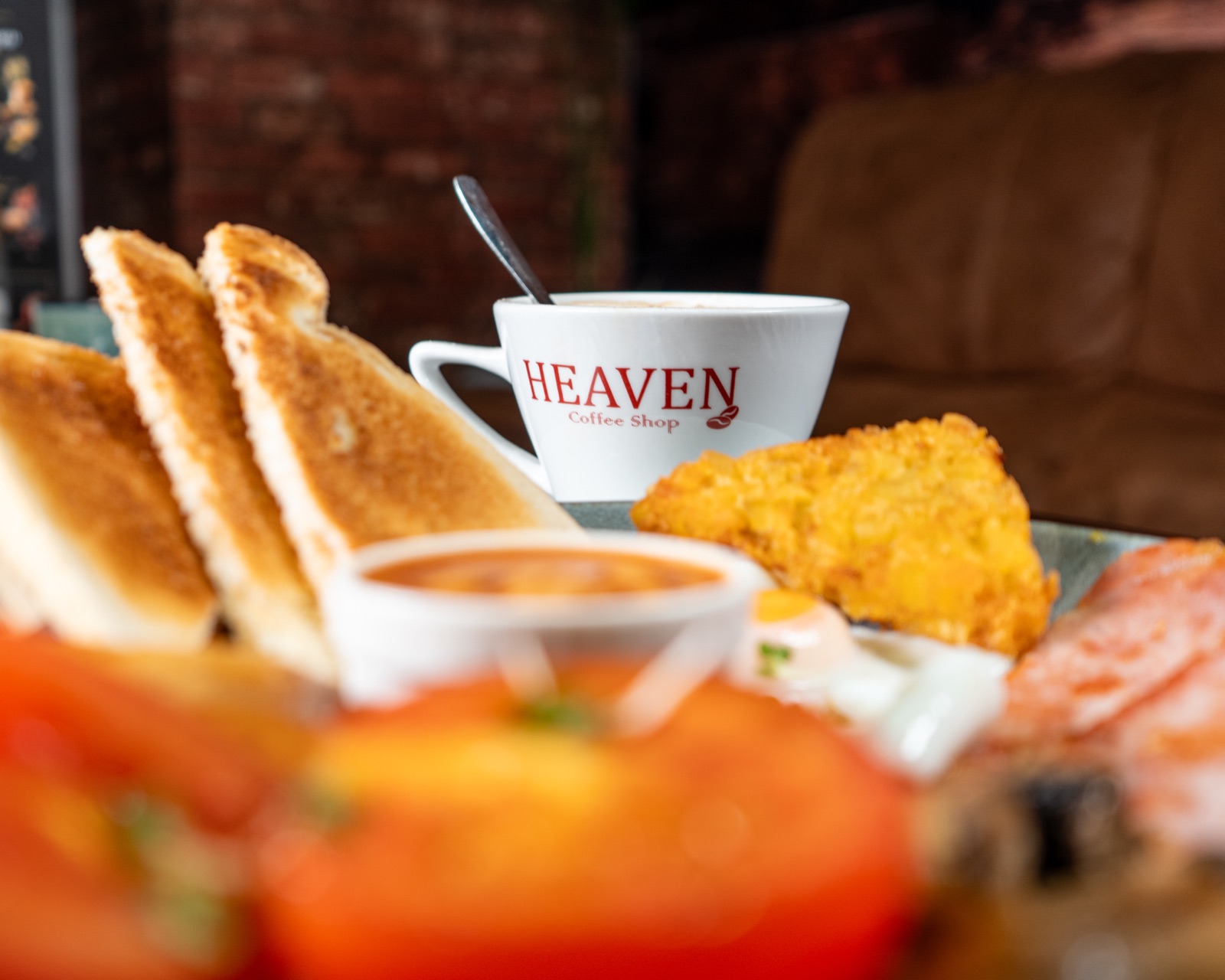 A Heaven breakfast with toast, eggs, bacon, sausage, beans and a branded coffee cup.